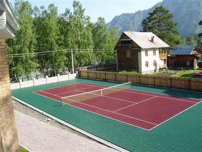 Outdoor sports court with a green and red surface, featuring a tennis net.