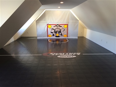 Indoor hockey practice area with black flooring, a hockey net, and a central logo in Waterford.