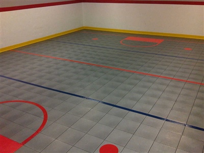 Indoor sports court with grey flooring and multiple colorful floor markings. 