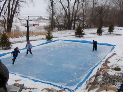 Outdoor ice hockey rink with a basketball hoop and kids skating.