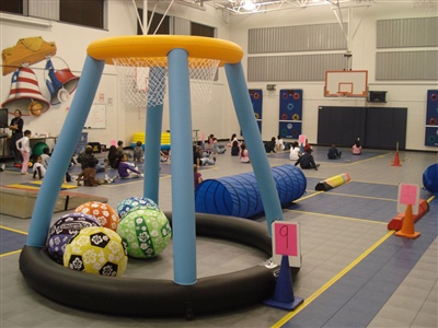 Multipurpose indoor sport court with grey and blue flooring and yellow borders with an obstacle course laid out.