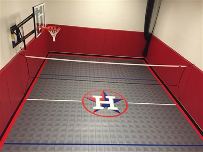 Indoor basketball and volleyball court with a grey tiled floor featuring a large "H" logo in the center, red padded walls, and a basketball hoop in Waconia.