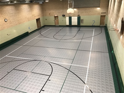 An indoor basketball court with a grey and green surface and black and white lines in Mendota Heights. 