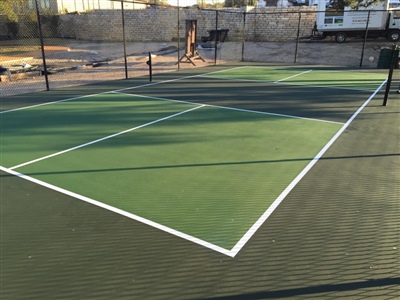 Outdoor sports court with a green surface and white lines, surrounded by a black fence in Grant.